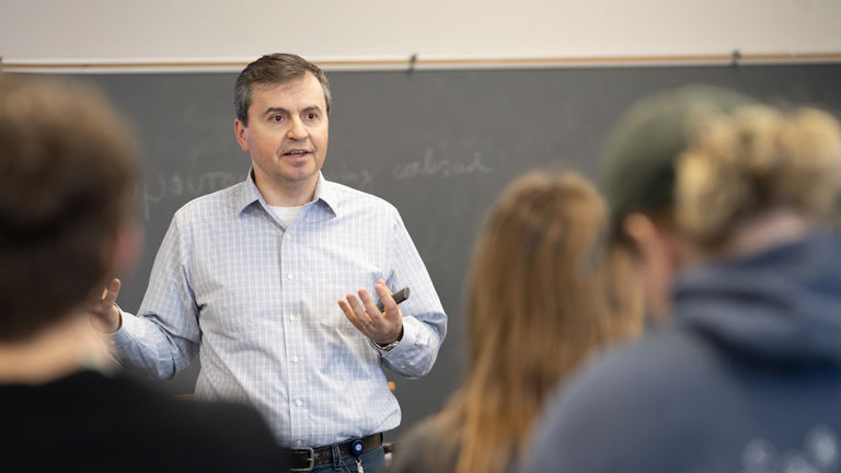 A professor in front of the classroom speaking to students.